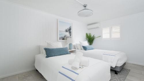 a white bedroom with two beds and a couch at Seaside Sanctuary - Waterfront Luxury Home with Heated Pool in Salamander Bay