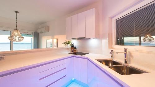 a kitchen with white cabinets and a sink and a window at Riviera - Panoramic Water Views In The Heart Of Nelson Bay in Nelson Bay