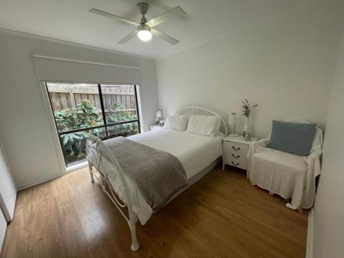 a white bedroom with a bed and a window at Dromana Panoramic Views in Dromana