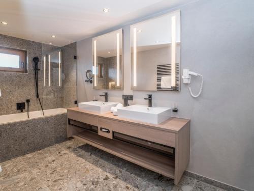 a bathroom with two sinks and a large mirror at Aktiv Hotel Schweizerhof Kitzbühel in Kitzbühel