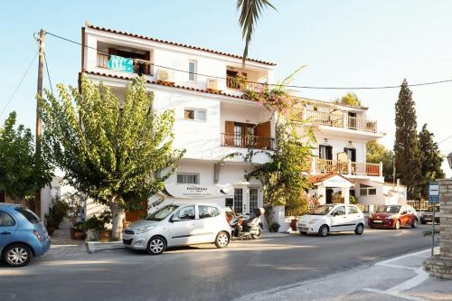 a white building with cars parked in front of it at Potokaki Beachfront Hotel in Pythagoreio