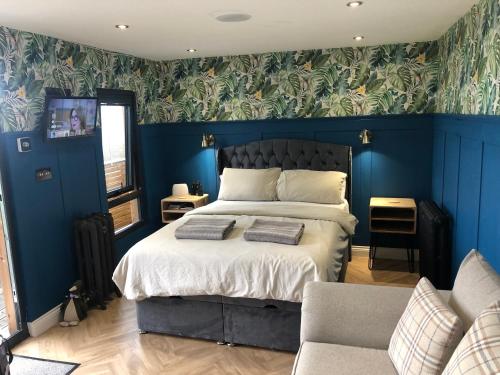 um quarto com uma cama com paredes azuis e um sofá em The Caswell bay hide out em Swansea