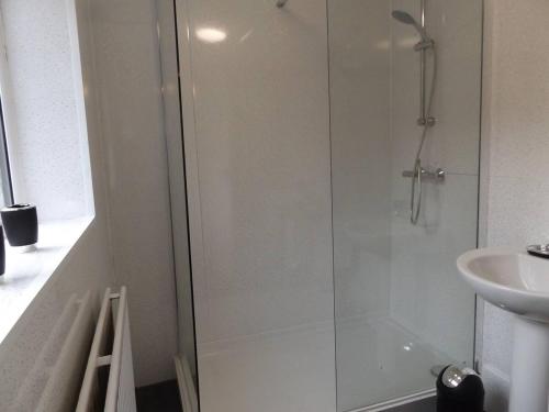 a shower with a glass door next to a sink at Forest Park House in Hanley