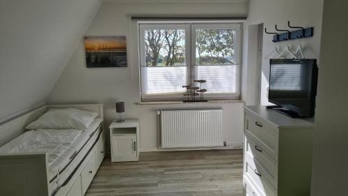 1 dormitorio con 1 cama, TV y ventana en Ferienhaus Hoddebüll nah an der Nordsee, en Emmelsbüll-Horsbüll
