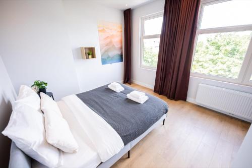 a bedroom with a bed and two windows at Premium 2 Bedroom Serviced Apartment 71M2 -VP2C- in Rotterdam