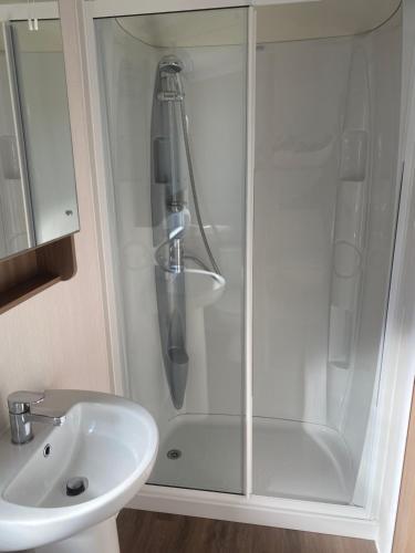 una ducha con una puerta de cristal junto a un lavabo en Craig Tara Glen Haven Caravan Dunure Village, en Ayr