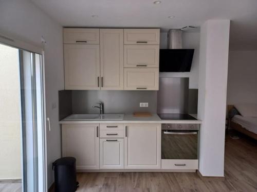 a kitchen with white cabinets and a sink at Grand studio neuf à Carry le Rouet in Carry-le-Rouet