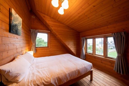 a bedroom with a bed in a wooden cabin at Suite Villa Ichinomiya Surf in Ichinomiya
