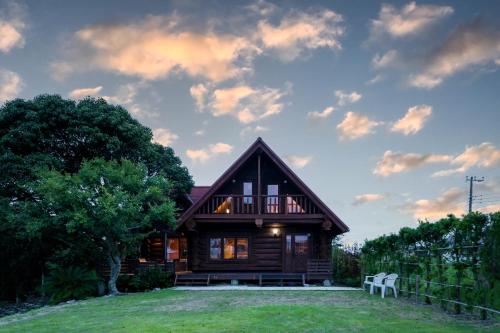 a log home with two white chairs in front of it at Suite Villa Ichinomiya Surf in Ichinomiya