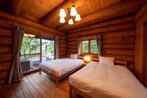 a bedroom with two beds in a log cabin at Suite Villa Ichinomiya Surf in Ichinomiya