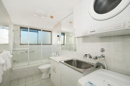 La salle de bains blanche est pourvue d'un lavabo et de toilettes. dans l'établissement Voyager Resort, à Gold Coast