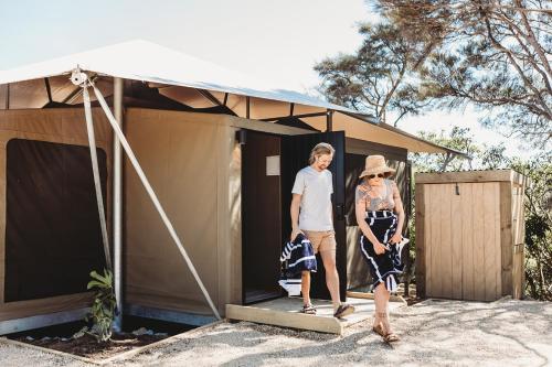 a man and woman standing outside of a tiny house at Drift Off Grid Luxury Eco Glamping in Tarakohe