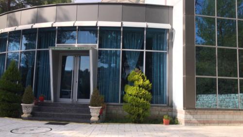 a large glass building with a revolving door at Kodra E Gjelber in Hundëkuq