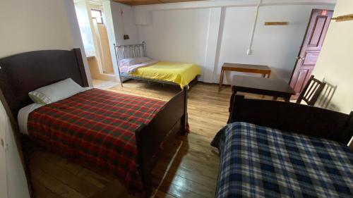 a room with two beds and a table and chairs at Hostal La Guayunga RoofTop in Quito