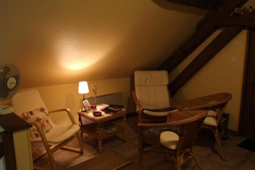 a living room with chairs and a table and a lamp at Le Clos de Châtres in Oisly
