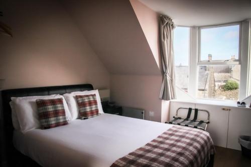 een slaapkamer met een bed met kussens en een raam bij Nort Bode Apartments in Lerwick