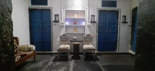 烏代浦的住宿－Madan Mohan Villas (A Haritage Haveli Home Stay)，一间设有2扇蓝色门和2把椅子的房间