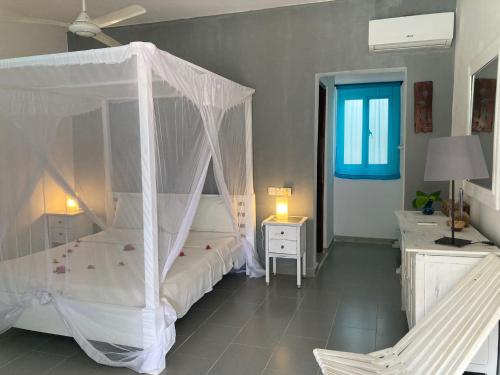 a bedroom with a canopy bed and a chair at Kibanda Lodge and Beach Club in Nungwi