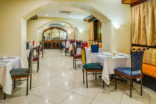 uma sala de jantar com mesas e cadeiras num restaurante em Bulawayo Rainbow Hotel em Bulawayo