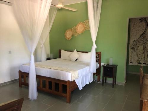 um quarto com uma cama com cortinas brancas em Kibanda Lodge and Beach Club em Nungwi