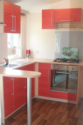 a kitchen with red cabinets and a sink and a stove at Altogold Swiss Holidays At Manor Farm 5* in Interlaken