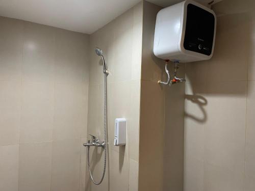 um chuveiro na casa de banho com uma televisão na parede em Stay G Service Residence Jatibening em Kaliastana