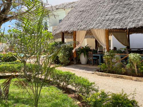 a house with a thatched roof with people sitting at a table at Kibanda Lodge and Beach Club in Nungwi