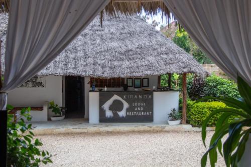 a sign in front of a building with a thatch roof at Kibanda Lodge and Beach Club in Nungwi