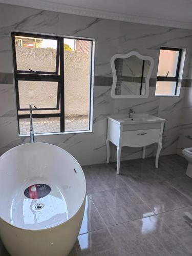 フーリーズバーグにあるDomsa Lapeng Guesthouseの浴槽、洗面台、鏡のあるバスルーム