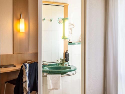 a bathroom with a green sink and a mirror at ibis Antwerpen Centrum in Antwerp