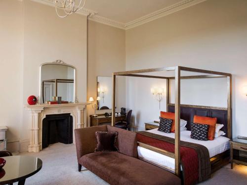 a bedroom with a canopy bed and a couch at Mercure Warwickshire Walton Hall Hotel & Spa in Wellesbourne Hastings