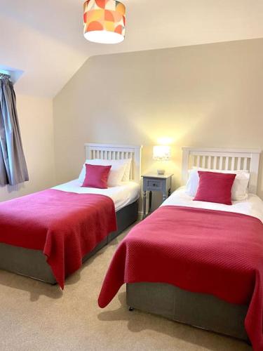 a bedroom with two beds with red sheets at Lion Cottage, Broadway in Broadway