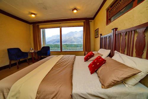 een groot bed in een kamer met een groot raam bij Baltistan Fort Skardu Resort in Skardu