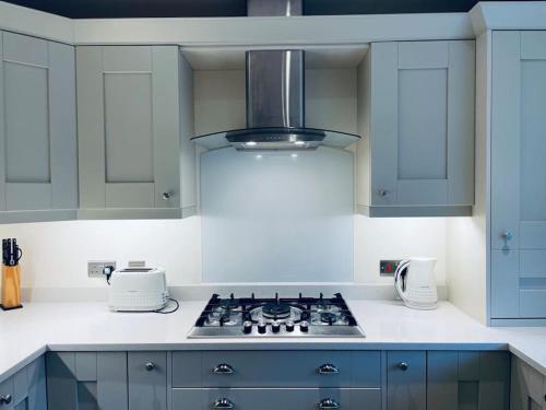 a kitchen with blue cabinets and a stove top oven at Lion Cottage, Broadway in Broadway