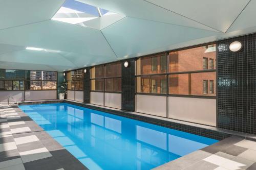 a large swimming pool with blue water in a building at Adina Apartment Hotel Melbourne in Melbourne