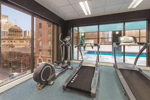 a gym with two treadmills and a swimming pool at Adina Apartment Hotel Melbourne in Melbourne