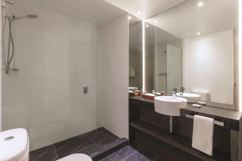 a bathroom with a sink and a mirror at Adina Apartment Hotel Melbourne in Melbourne