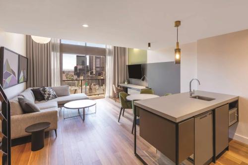 a kitchen and living room with a couch and a table at Adina Apartment Hotel Melbourne in Melbourne