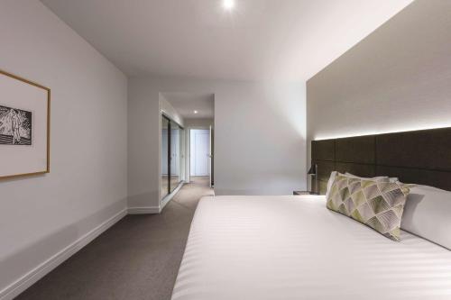 a bedroom with a large white bed with a black headboard at Adina Apartment Hotel Melbourne in Melbourne