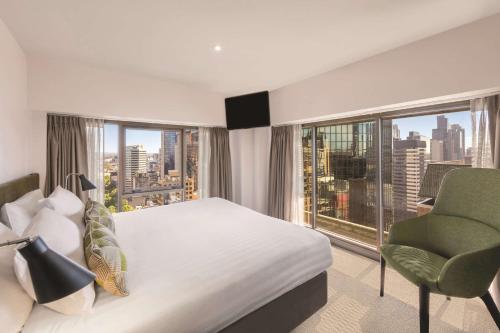 a bedroom with a bed and a chair and a window at Adina Apartment Hotel Melbourne in Melbourne