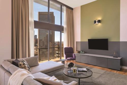 a living room with a couch and a tv at Adina Apartment Hotel Melbourne in Melbourne