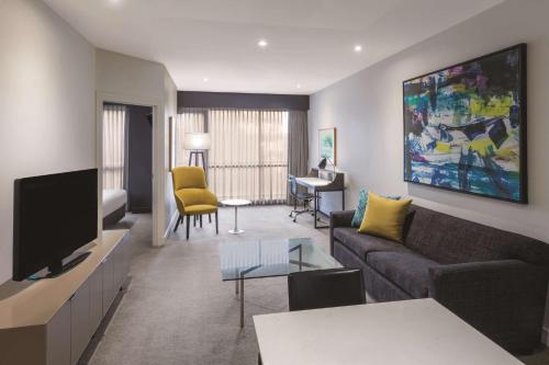 a living room with a couch and a tv at Adina Apartment Hotel Melbourne in Melbourne