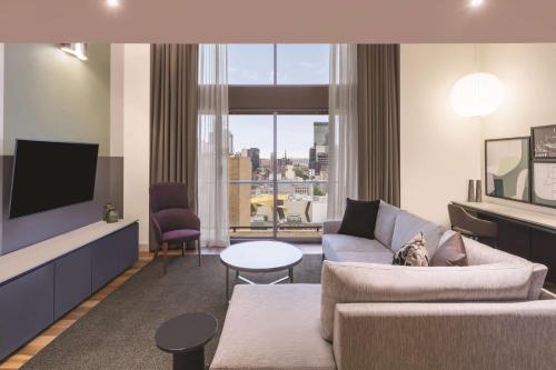 a living room with a couch and a tv at Adina Apartment Hotel Melbourne in Melbourne