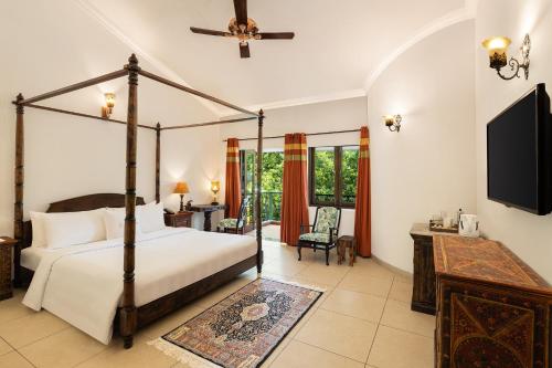 1 dormitorio con cama con dosel y TV en Storii By ITC Hotels, Shanti Morada Goa en Calangute