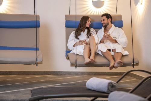 a man and woman sitting on beds in a gym at Ferien & Wellnesshotel Windschar in Brunico