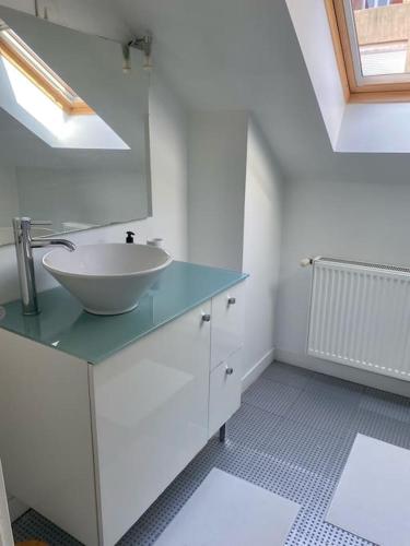 uma casa de banho branca com um lavatório e um espelho em Malo les bains: duplex à deux pas de la plage. em Dunkerque