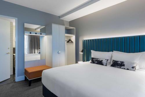 a bedroom with a white bed and a blue wall at Adina Apartment Hotel Brisbane in Brisbane