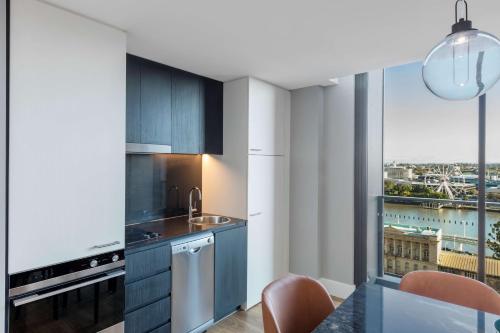 a kitchen with blue cabinets and a large window at Adina Apartment Hotel Brisbane in Brisbane