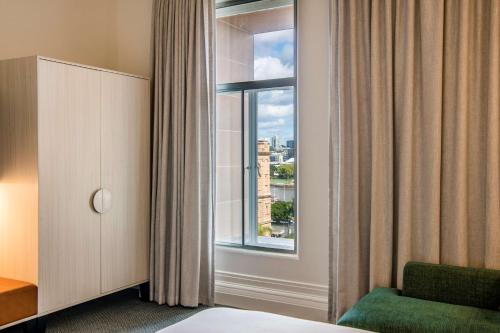 a room with a bed and a window and a chair at Adina Apartment Hotel Brisbane in Brisbane