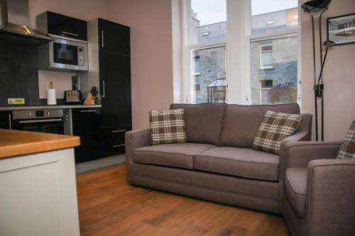 ein Wohnzimmer mit einem Sofa und einer Küche in der Unterkunft Nort Bode Apartments in Lerwick
